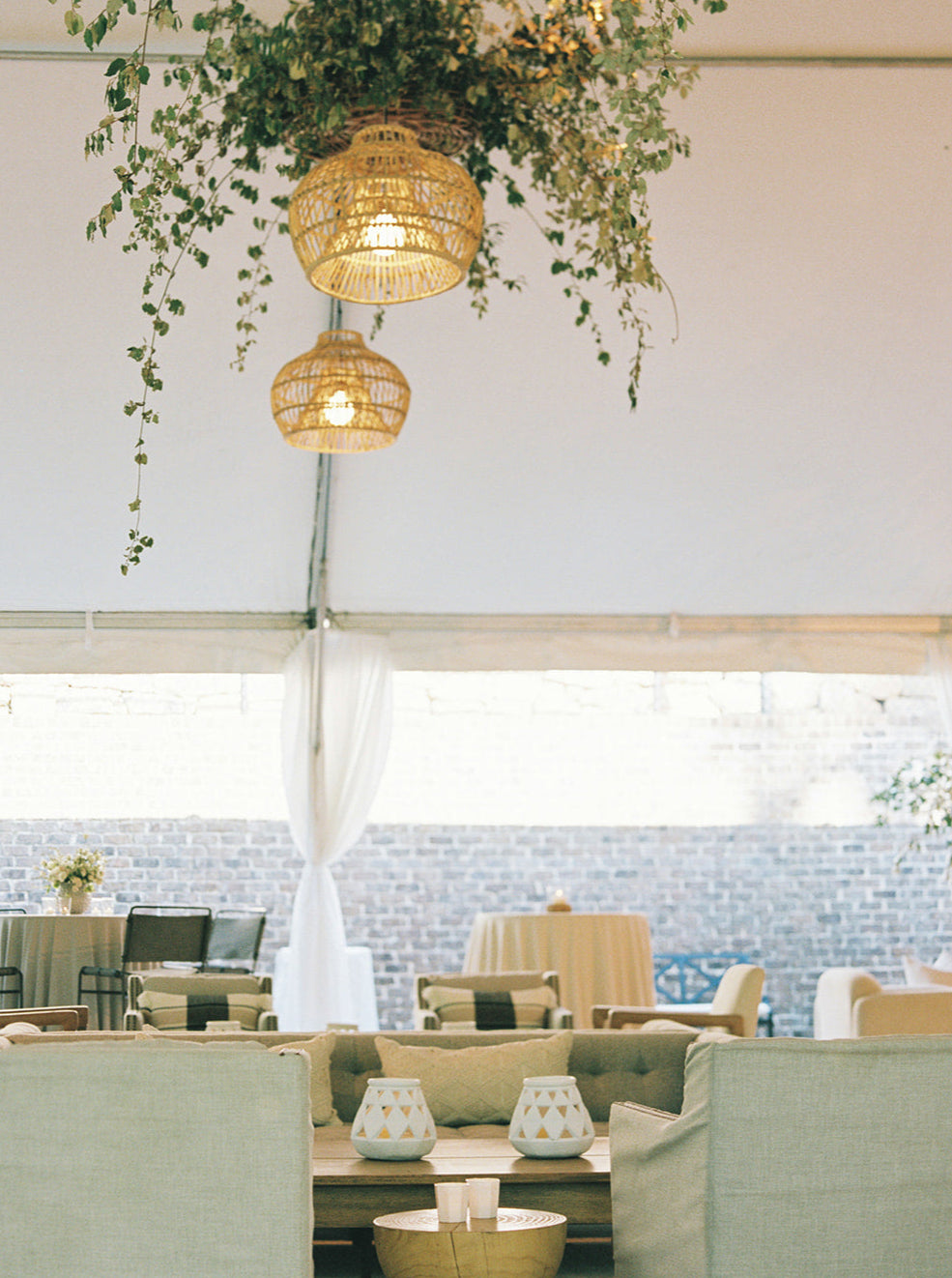 Indoor setting with hanging plants and wicker lanterns above a dining area.