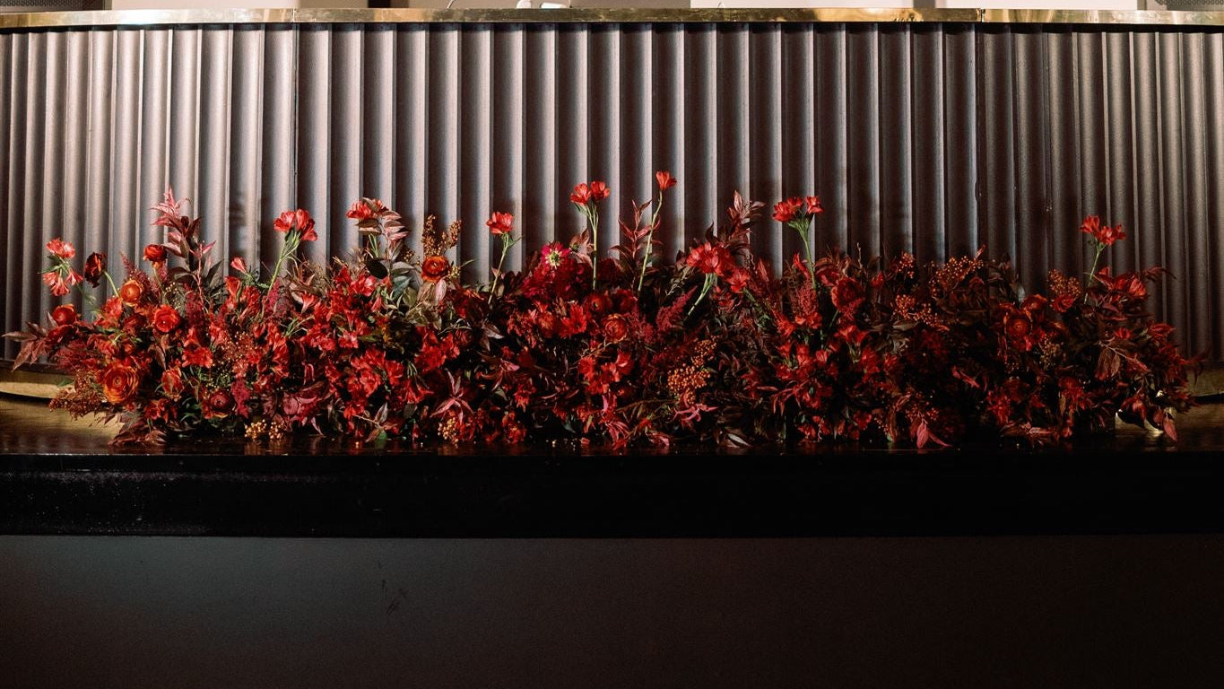 Red flowers arranged in a pattern against a corrugated metal background